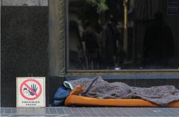 Persona durmiendo en la calle tapada con una frazada
